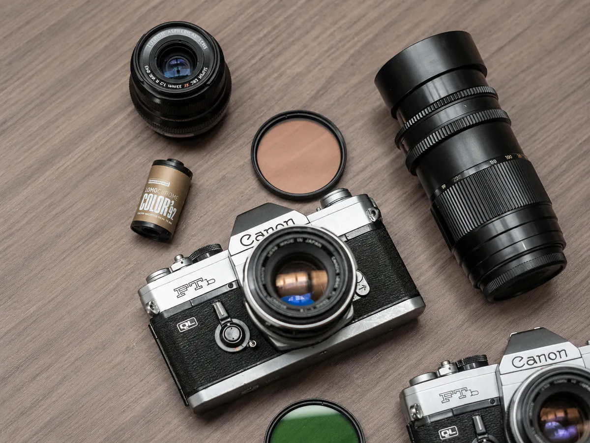 Aparat Canon leżący na stoliku obok filtrów i obiektywów